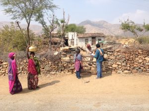 People in an Indian village, dirt road, rock fence